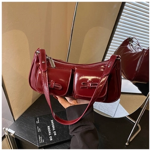 Detailed macro view of glossy burgundy patent leather shoulder bag with bow accents