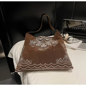Nahaufnahme der kaffeebraunen Wildleder-Tragetasche mit weißer Paisley-Stickerei