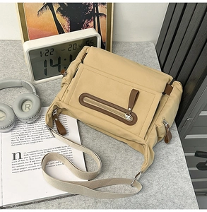Detail of khaki messenger bag showing multiple zipper pockets and adjustable strap