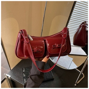 Close-up of wine red patent leather shoulder bag with glossy finish and bow details