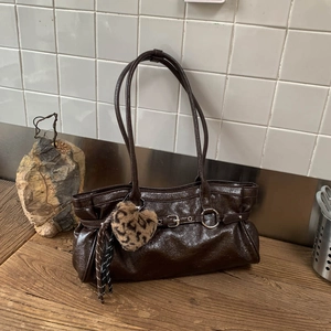 Détail du sac à main marron foncé brillant avec breloque cœur léopard et anneau métal