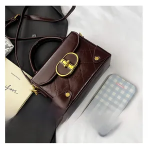 Detail view of burgundy quilted mini bag with golden oval lock and retro styling