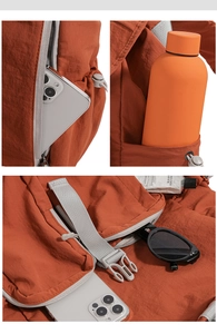 Detail view of the orange nylon backpack showing side zipper pocket and drawstring water bottle holder