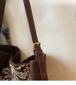 Detail der braunen Wildledertasche mit weißer Stickerei und verstellbarer Gold-Schnalle