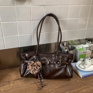 Détail d'un sac à bandoulière en cuir verni marron foncé avec pendentif léopard