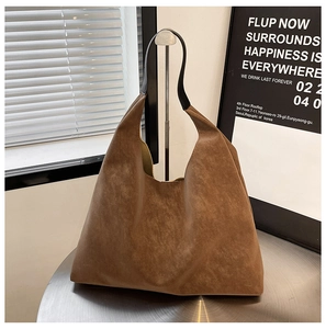 Close-up of a brown matte hobo tote bag on a silver metal table with soft lighting