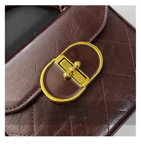 Detailed macro view of the vintage wine red quilted leather bag with gold metal clasp