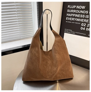 Detail of vintage brown suede tote bag on metal stand with modern minimalist studio decor