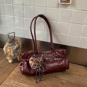 Détail du sac à main bordeaux brillant avec pendentif cœur léopard sur fond vintage