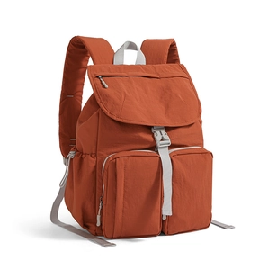 Close-up of orange backpack features with flap buckle and dual front zipper pockets