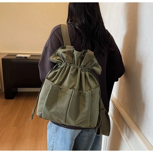 Detail of army green bucket backpack with drawstring closure and metal buckle pockets