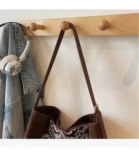 Detaillierte Stickerei weißer Blumenmuster auf brauner Wildledertasche mit Schnalle
