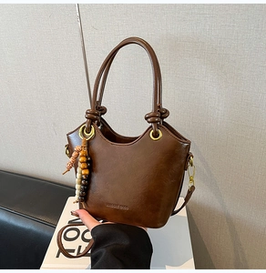 Detail of vintage brown bucket bag with metal ring handle and beaded keychain