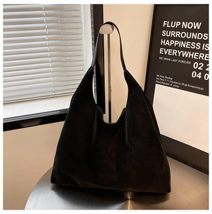 Detail of minimalist black matte tote bag hanging on a modern silver metal stand
