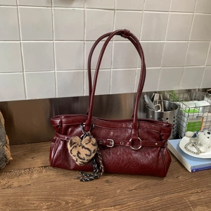 Détail du sac fourre-tout bordeaux avec œillets métalliques et breloque cœur léopard