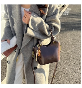 Detail of vintage dark brown bucket bag with gold ring and decorative wooden beads