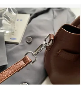 Détail de la boucle argentée et texture litchi sur un sac seau en cuir marron
