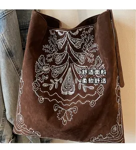 Nahaufnahme der braunen Wildleder-Tragetasche mit weißer Blumen-Stickerei und Lederriemen
