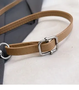 Detailed macro view of an adjustable brown leather bag strap with silver metal buckle