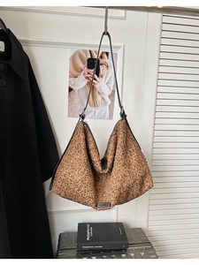 Vue détaillée du grand sac cabas léopard avec fines lanières noires sur une porte blanche