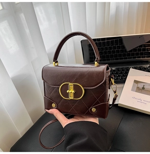 Detail of dark brown quilted leather crossbody bag with gold hardware on office desk