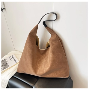 Detail shot of brown matte tote bag with wide black shoulder strap and minimalist texture