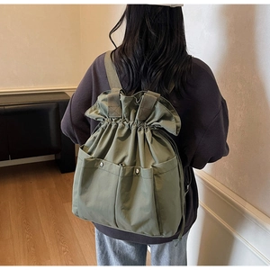 Detail view of army green drawstring bucket backpack with front metal snap pockets