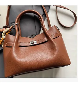 Détail du sac cabas marron à texture litchi avec fermoir tournant en métal et breloque