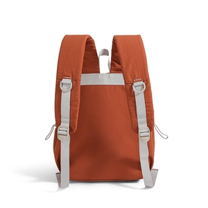 Detail view of brick red nylon backpack featuring padded shoulder straps and D-ring hooks