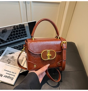 Detailed view of brown leather handbag with gold metal clasp and diamond quilt stitching