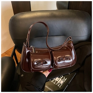 Detail of dark brown glossy leather shoulder bag with two pockets and bow decorations