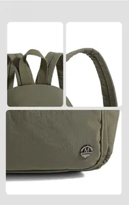 Detail of olive green nylon backpack handles, reinforced stitching and metal logo