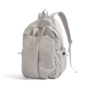 Detail of light grey grid pattern backpack with reinforced straps and side mesh pockets