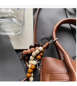 Gros plan d'un charme en perles de bois vintage avec fermoir sur un sac seau en cuir