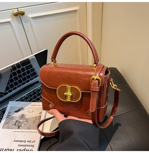 Detail of a brown quilted leather crossbody bag with a gold metal twist lock