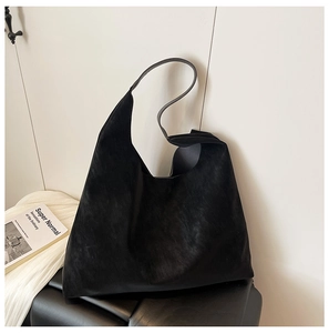 Detail of minimalist black frosted tote bag on leather bench with modern aesthetic