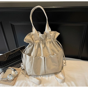 Detailed view of beige canvas bucket bag with drawstring closure and large front pockets
