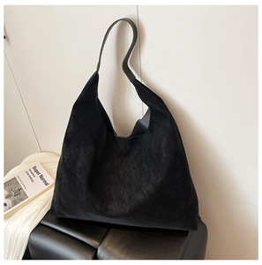 Minimalist black matte suede tote bag displayed elegantly on a modern black leather stool