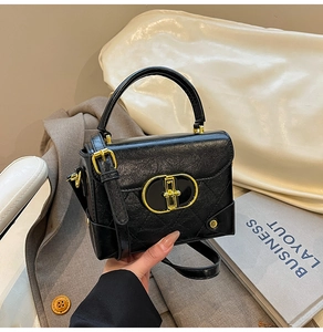 Detail of vintage black crossbody bag with diamond quilting and gold buckle hardware