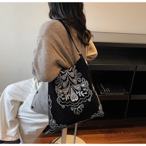 Detail einer großen schwarzen Wildleder-Einkaufstasche mit weißer Stickerei im Casual-Stil