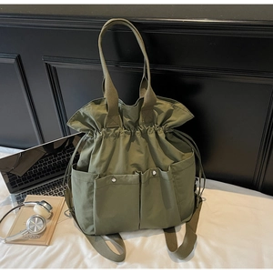 Detail of army green canvas bucket bag with drawstring closure and front utility pockets