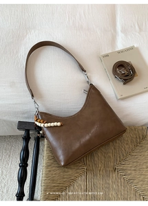 Close-up of vintage dark brown bucket bag with textured leather and wooden bead charm