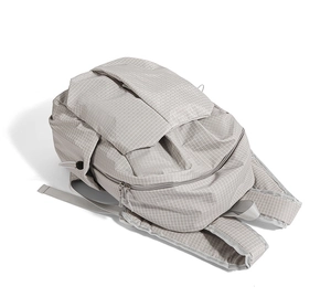 Detail of light grey grid textured backpack showing side adjustable drawstring and strap