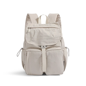 Close-up of beige waterproof nylon backpack featuring dual front zipper pockets and drawstring side bags