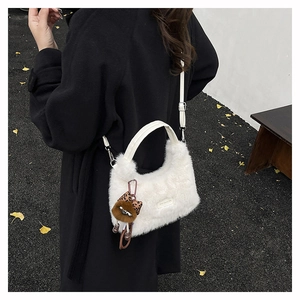 Close-up of white plush handbag with leather handle, silver hardware and a cute charm