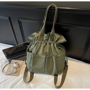 Detail view of army green bucket backpack with drawstring closure and large front pockets