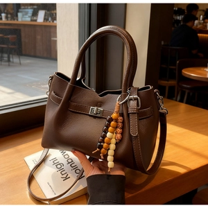 Détail du sac seau en cuir grainé marron foncé avec fermoir argenté et breloque
