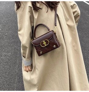 Detail of vintage brown crossbody bag with gold buckle and quilted side on beige coat
