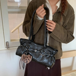 Détail d'un sac à main en cuir PU noir brillant avec un pendentif coeur en peluche léopard