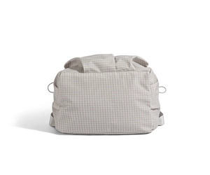 Close-up detail of light gray checkered fabric texture and side drawstring pocket on backpack